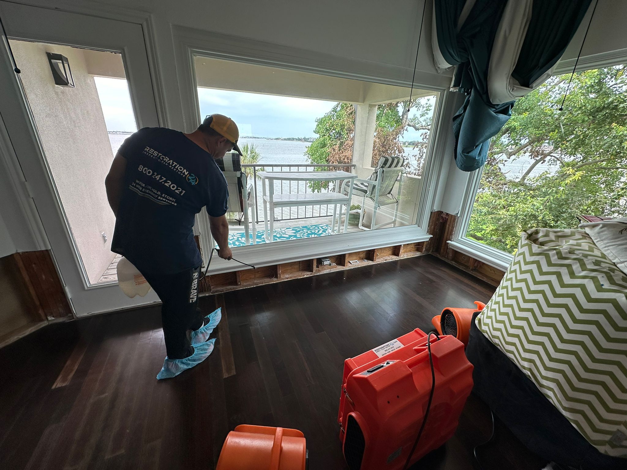 Technician applying disinfectant to water-damaged walls with drying equipment.